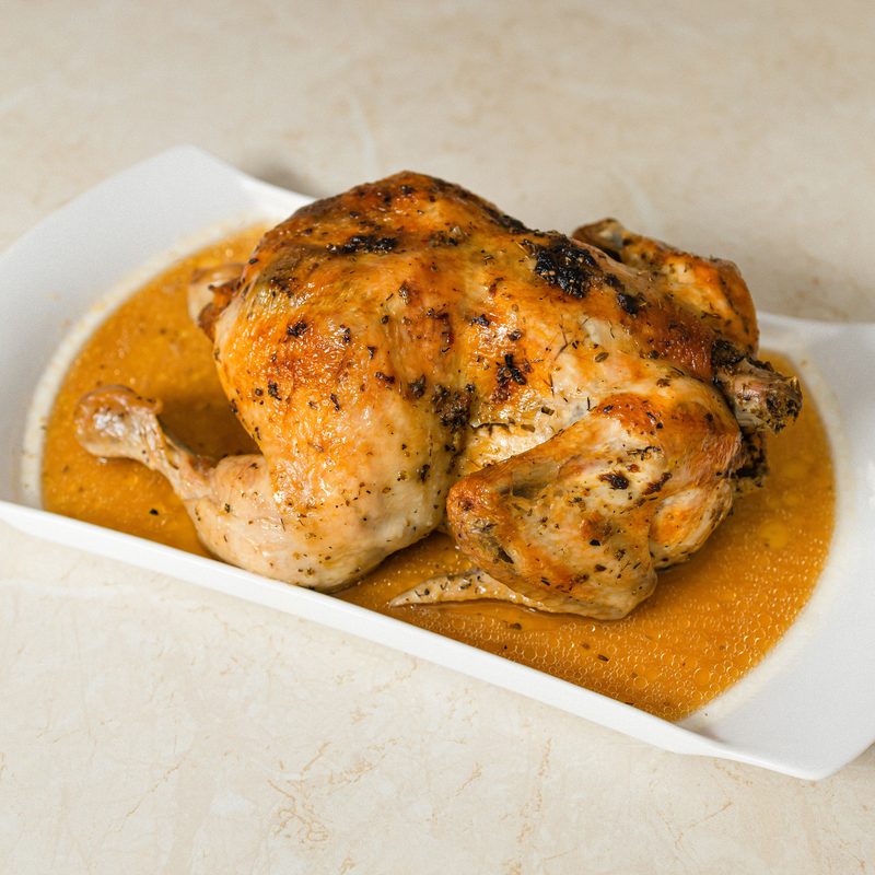 Roast chicken in sauce on a white platter